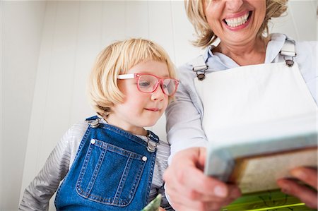 Mature woman sitting on kitchen counter reading storybook with daughter Stock Photo - Premium Royalty-Free, Code: 649-08894316