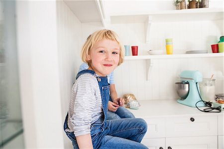 Portrait of cute girl sitting in front of brother on kitchen counter Stock Photo - Premium Royalty-Free, Code: 649-08894312