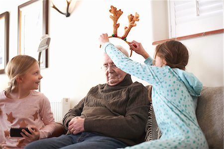 extended family at christmas - Sisters putting reindeer antlers on sleeping grandfather Stock Photo - Premium Royalty-Free, Code: 649-08894380