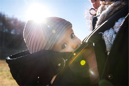 Sunlit close up of baby boy wearing knit hat, carried in baby sling by mother Stock Photo - Premium Royalty-Free, Code: 649-08894406