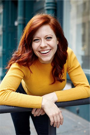 redhead woman smiling portrait - Portrait of young woman with red hair, leaning on fence, smiling Stock Photo - Premium Royalty-Free, Code: 649-08894495
