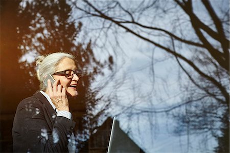 simsearch:614-06814076,k - Home window view of senior businesswoman making smartphone call Stock Photo - Premium Royalty-Free, Code: 649-08894602