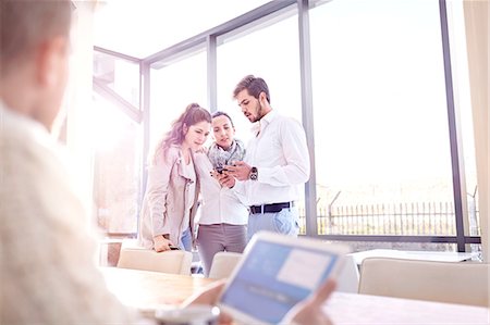 simsearch:614-08877313,k - Over shoulder view of young businessman and women looking at smartphone in office Stock Photo - Premium Royalty-Free, Code: 649-08894713