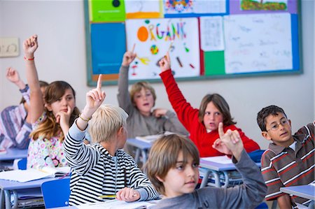 Students in classroom, sitting at desks, with arms raised Stock Photo - Premium Royalty-Free, Code: 649-08894812