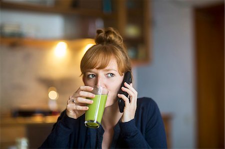 single woman at home - Young woman drink smoothie, using smartphone Stock Photo - Premium Royalty-Free, Code: 649-08894832