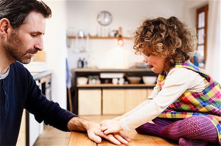 Girl on table sticking adhesive plaster onto father's hand Photographie de stock - Premium Libres de Droits, Code: 649-08894903