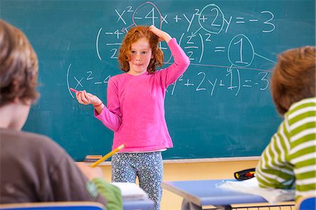 Primary schoolgirl scratching her head at equation on classroom blackboard Stock Photo - Premium Royalty-Free, Code: 649-08895120
