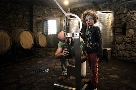 simsearch:649-08895214,k - Boy with winemaker corking wine bottle in cellar Photographie de stock - Premium Libres de Droits, Code: 649-08895197