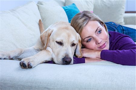 simsearch:649-08714973,k - Mid adult woman lying on sofa with her labrador dog Foto de stock - Sin royalties Premium, Código: 649-08900415
