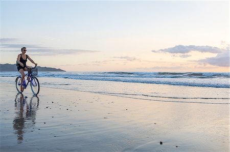 pacific coast people - Woman cycling on beach at sunset, Nosara, Guanacaste Province, Costa Rica Stock Photo - Premium Royalty-Free, Code: 649-08900718