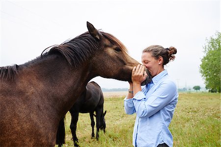 Woman with her face to horse's muzzle in field Photographie de stock - Premium Libres de Droits, Code: 649-08900812
