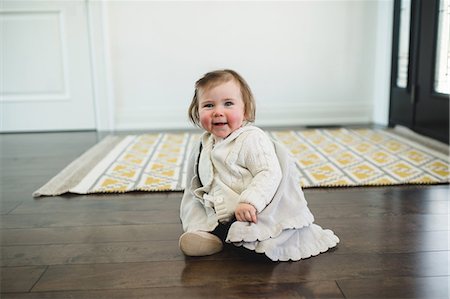 rosy cheeks - Rosy-cheeked baby sitting on the floor smiling Stock Photo - Premium Royalty-Free, Code: 649-08900916