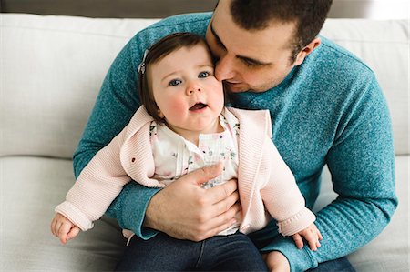 dad daughter snuggle - Baby girl looking up while being snuggled by her father Stock Photo - Premium Royalty-Free, Code: 649-08900919