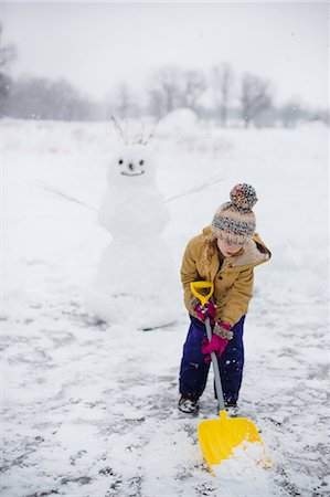 Girl shovelling snow in front of snowman, Lakefield, Ontario, Canada Fotografie stock - Premium Royalty-Free, Codice: 649-08900944