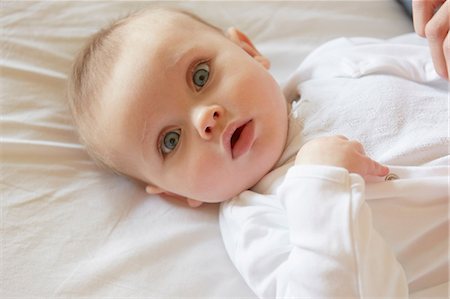 simsearch:614-08881045,k - Portrait of blue eyed baby girl lying on bed Fotografie stock - Premium Royalty-Free, Codice: 649-08900995