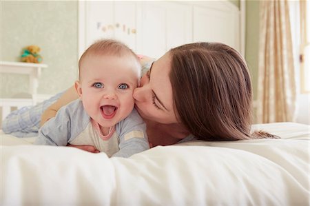 simsearch:649-08949462,k - Women lying on bed kissing baby daughter on cheek Stock Photo - Premium Royalty-Free, Code: 649-08901031