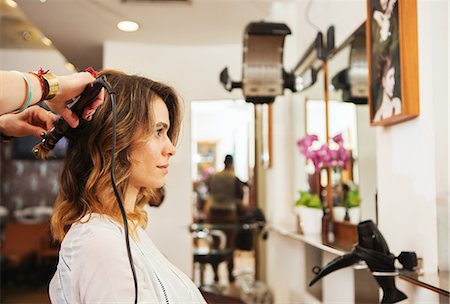 simsearch:614-09213780,k - Hairdresser using curling tongs on customer's long brown hair in salon Fotografie stock - Premium Royalty-Free, Codice: 649-08901355