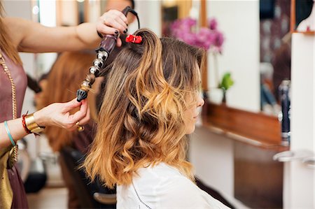 simsearch:614-09213780,k - Hairdresser using curling tongs on customer's long brown hair in salon Fotografie stock - Premium Royalty-Free, Codice: 649-08901357
