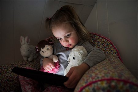 Female toddler sitting up in bed staring at digital tablet Stock Photo - Premium Royalty-Free, Code: 649-08901428