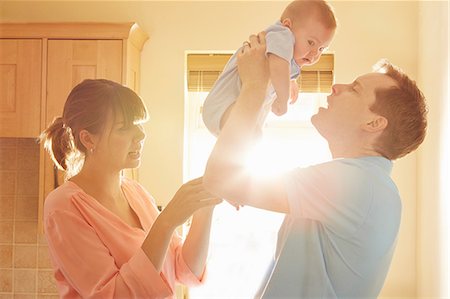 simsearch:614-09038702,k - Mature man with wife holding up baby son in sunlit kitchen Photographie de stock - Premium Libres de Droits, Code: 649-08901454