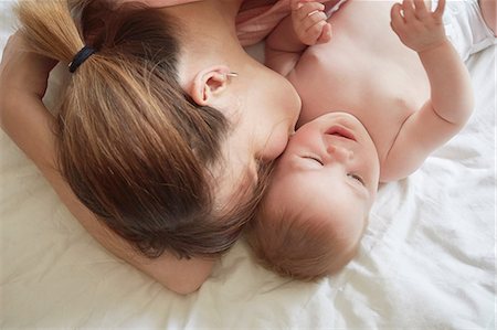 Overhead view of woman on bed kissing baby son on cheek Stock Photo - Premium Royalty-Free, Code: 649-08901479
