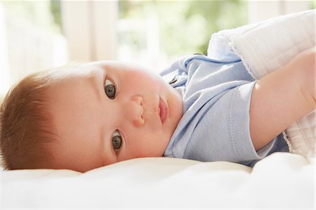 simsearch:614-08881045,k - Blue eyed baby boy lying on back on bed Fotografie stock - Premium Royalty-Free, Codice: 649-08901473