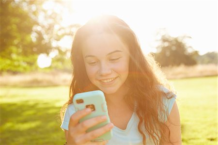 Girl looking at smartphone in sunlit park Photographie de stock - Premium Libres de Droits, Code: 649-08901490
