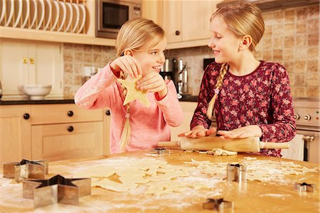 simsearch:614-08946604,k - Two girls baking star shape pastry at kitchen table Foto de stock - Royalty Free Premium, Número: 649-08901574