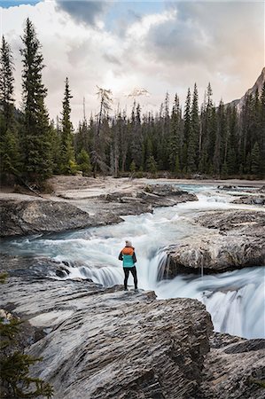 single landscape - Woman standing at edge of waterfall, looking at view, Natural Bridge Falls, Kicking Horse River, Yoho National Park, Field, British Columbia, Canada Stock Photo - Premium Royalty-Free, Code: 649-08901694