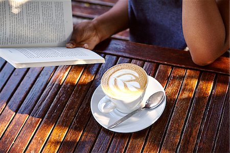reading book open air - Young woman sitting outdoors, reading book, coffee in front of her, mid section Stock Photo - Premium Royalty-Free, Code: 649-08901830