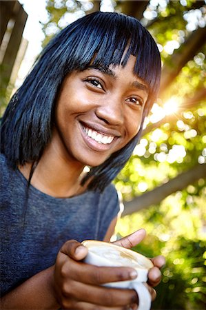 simsearch:649-08825304,k - Portrait of young woman sitting outdoors, holding coffee cup, smiling Stock Photo - Premium Royalty-Free, Code: 649-08901833