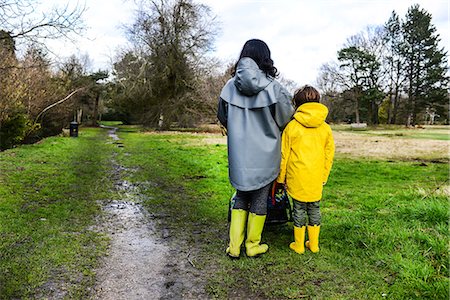Rear view of woman with son in yellow anorak standing in park Stock Photo - Premium Royalty-Free, Code: 649-08902294