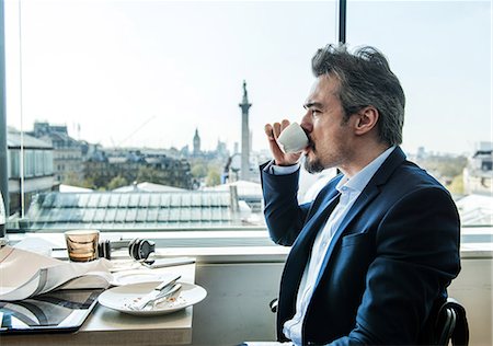 simsearch:649-08924139,k - Businessman drinking coffee by restaurant window with rooftops views, London, UK Fotografie stock - Premium Royalty-Free, Codice: 649-08924129