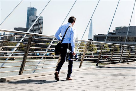 Businessman carrying scooter, Hungerford Bridge, London, UK Stock Photo - Premium Royalty-Free, Code: 649-08924137