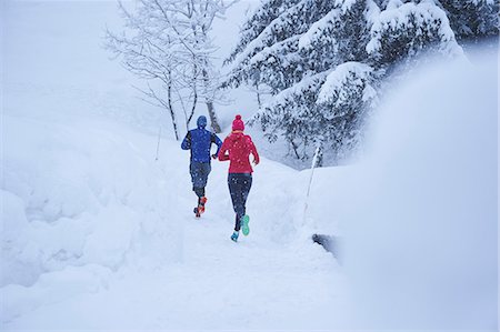 Rear view of male and female runners running on track in deep snow, Gstaad, Switzerland Stock Photo - Premium Royalty-Free, Code: 649-08924188