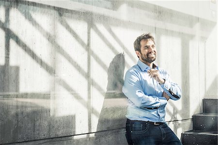 Confident businessman leaning against wall in office stairway Stock Photo - Premium Royalty-Free, Code: 649-08924240