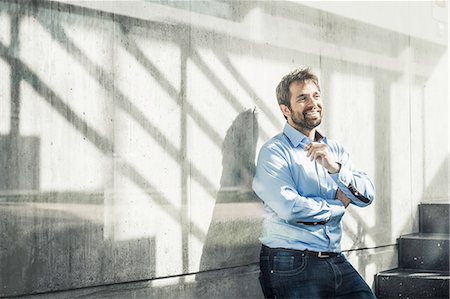 Confident businessman leaning against wall in office stairway Foto de stock - Sin royalties Premium, Código: 649-08924240