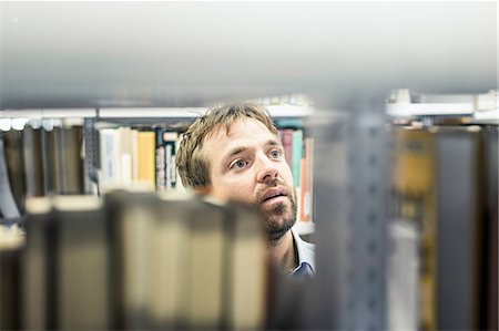 Businessman looking at file shelves in office storeroom Stock Photo - Premium Royalty-Free, Code: 649-08924242