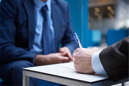 simsearch:632-08331722,k - Businessmen signing paperwork in office atrium, cropped Stock Photo - Premium Royalty-Free, Code: 649-08924288