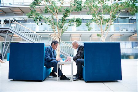 simsearch:649-08924433,k - Two businessmen having discussion meeting in office atrium armchairs Fotografie stock - Premium Royalty-Free, Codice: 649-08924291