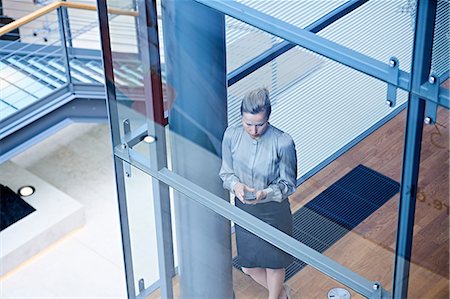 High angle view of businesswoman looking at smartphone on office stairway Stock Photo - Premium Royalty-Free, Code: 649-08924322