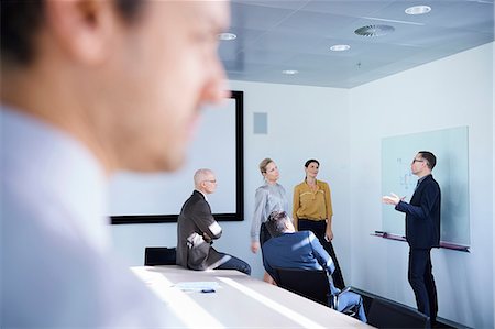 simsearch:649-07596189,k - Businessman making whiteboard presentation in conference room meeting Photographie de stock - Premium Libres de Droits, Code: 649-08924338