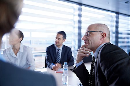 simsearch:614-06311939,k - Over shoulder view of businesswoman and men listening at office meeting Stock Photo - Premium Royalty-Free, Code: 649-08924356