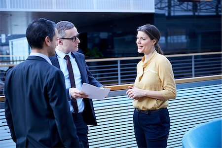 simsearch:649-08949847,k - Businesswoman and men with paperwork in office atrium Stock Photo - Premium Royalty-Free, Code: 649-08924400