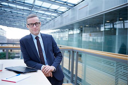 Portrait of businessman leaning against office balcony table Stock Photo - Premium Royalty-Free, Code: 649-08924403