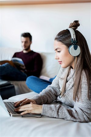 simsearch:614-08641562,k - Young couple relaxing at home, young woman using laptop, young man reading magazine Photographie de stock - Premium Libres de Droits, Code: 649-08924680