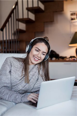 skype - Young woman relaxing at home, using laptop, wearing headphones Foto de stock - Sin royalties Premium, Código: 649-08924682