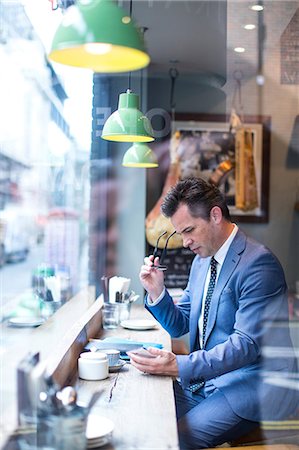 simsearch:649-08117870,k - Mature businessman looking at smartphone in restaurant window seat Photographie de stock - Premium Libres de Droits, Code: 649-08924904