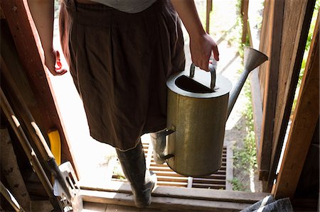 debajo de la cintura - Waist down view of woman carrying watering can in shed doorway Foto de stock - Sin royalties Premium, Código: 649-08924931