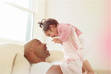 simsearch:649-08901538,k - Mid adult man on sofa holding up baby daughter Stock Photo - Premium Royalty-Free, Code: 649-08922859